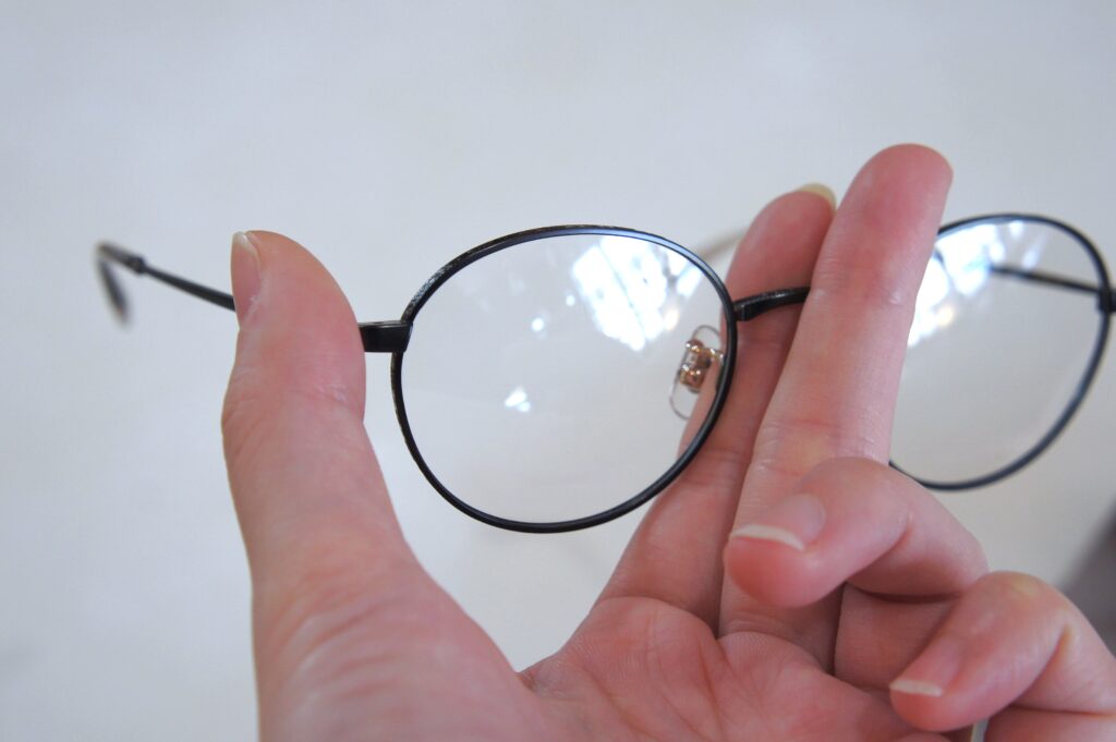 人差し指と中指でメガネのブリッジを挟み、親指でヨロイを支えてメガネを持っている写真
